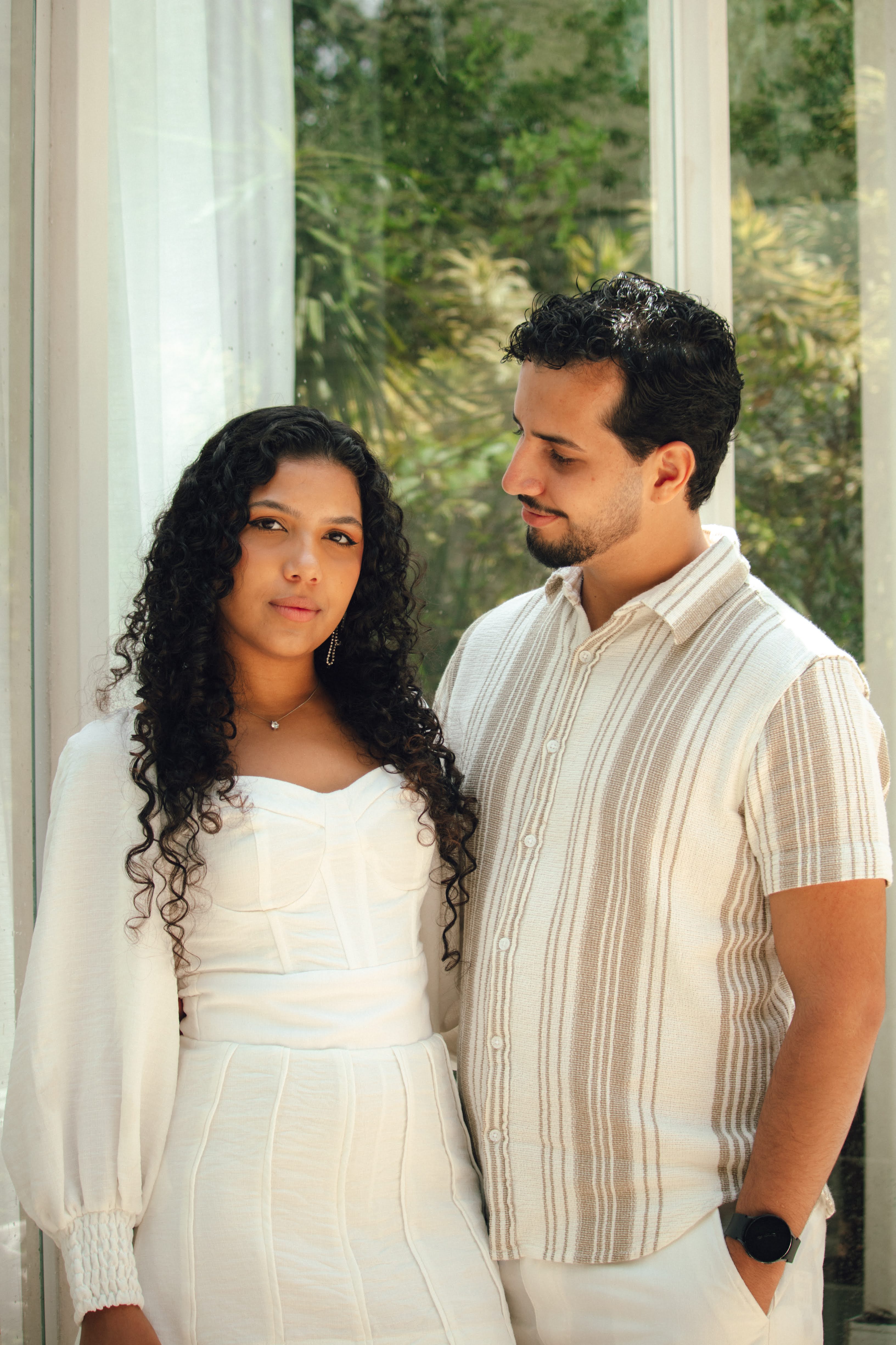 Emanuel e Melissa próximos a uma janela com luz natural suave