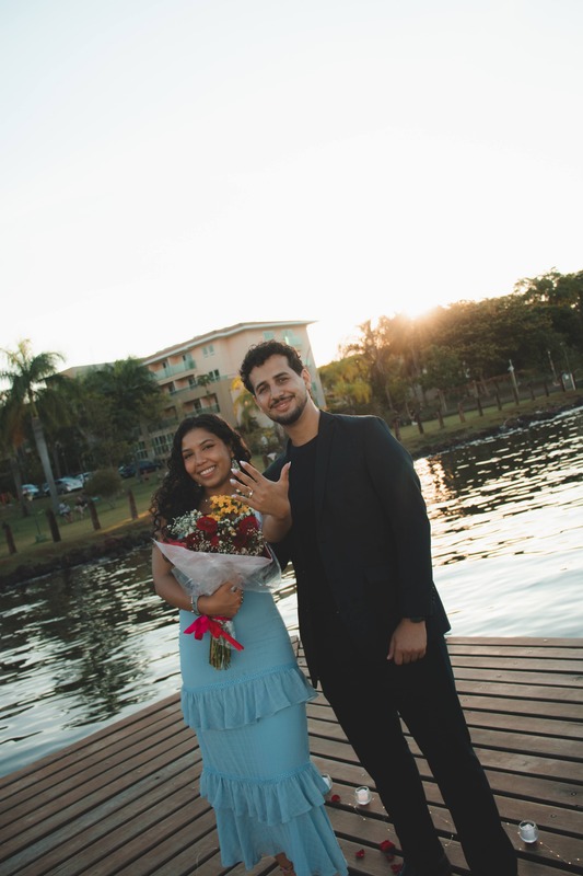 Emanuel e Melissa caminhando de mãos dadas no pier ao pôr do sol